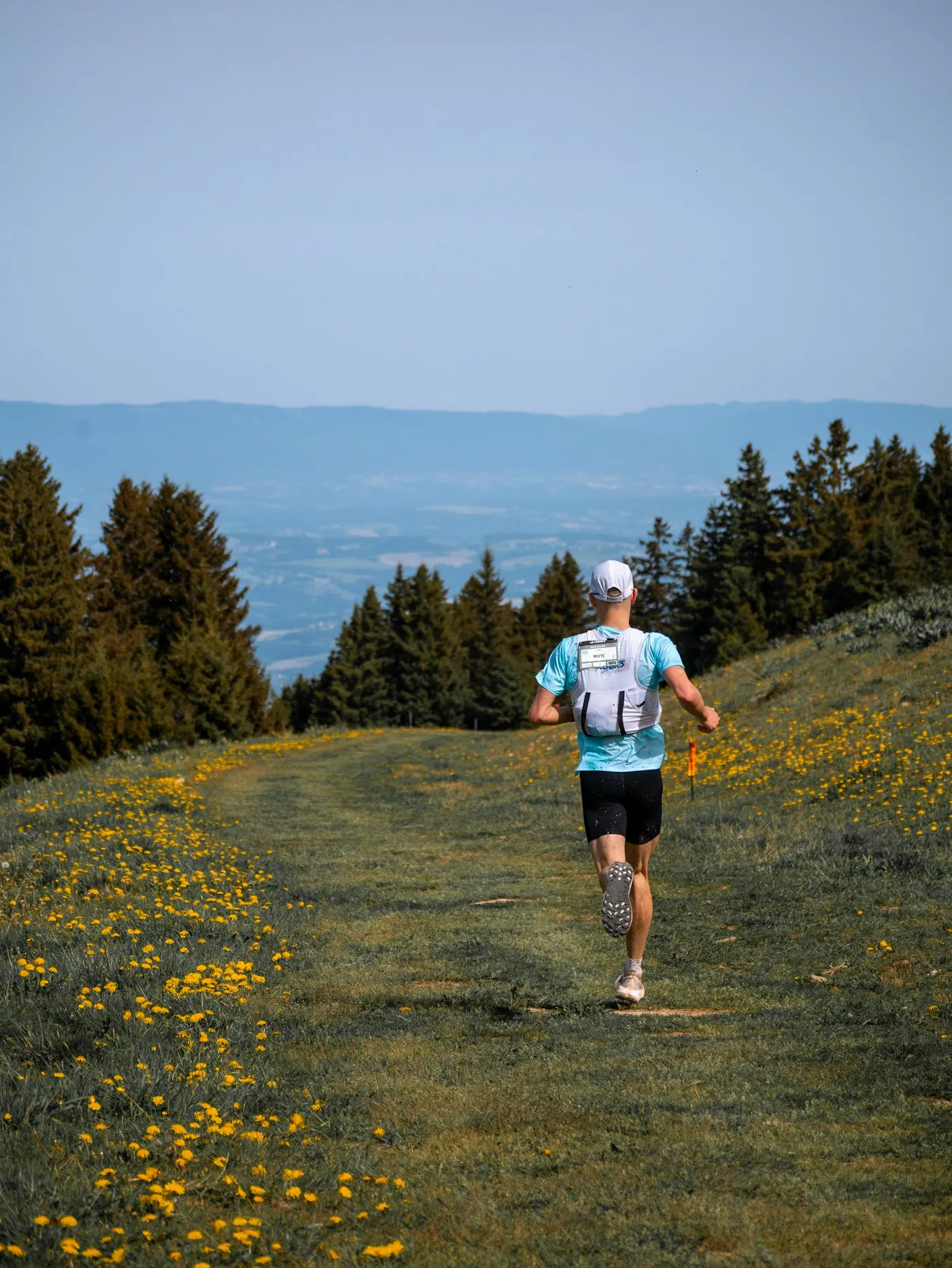 A trail runner climbing through wildflower meadows