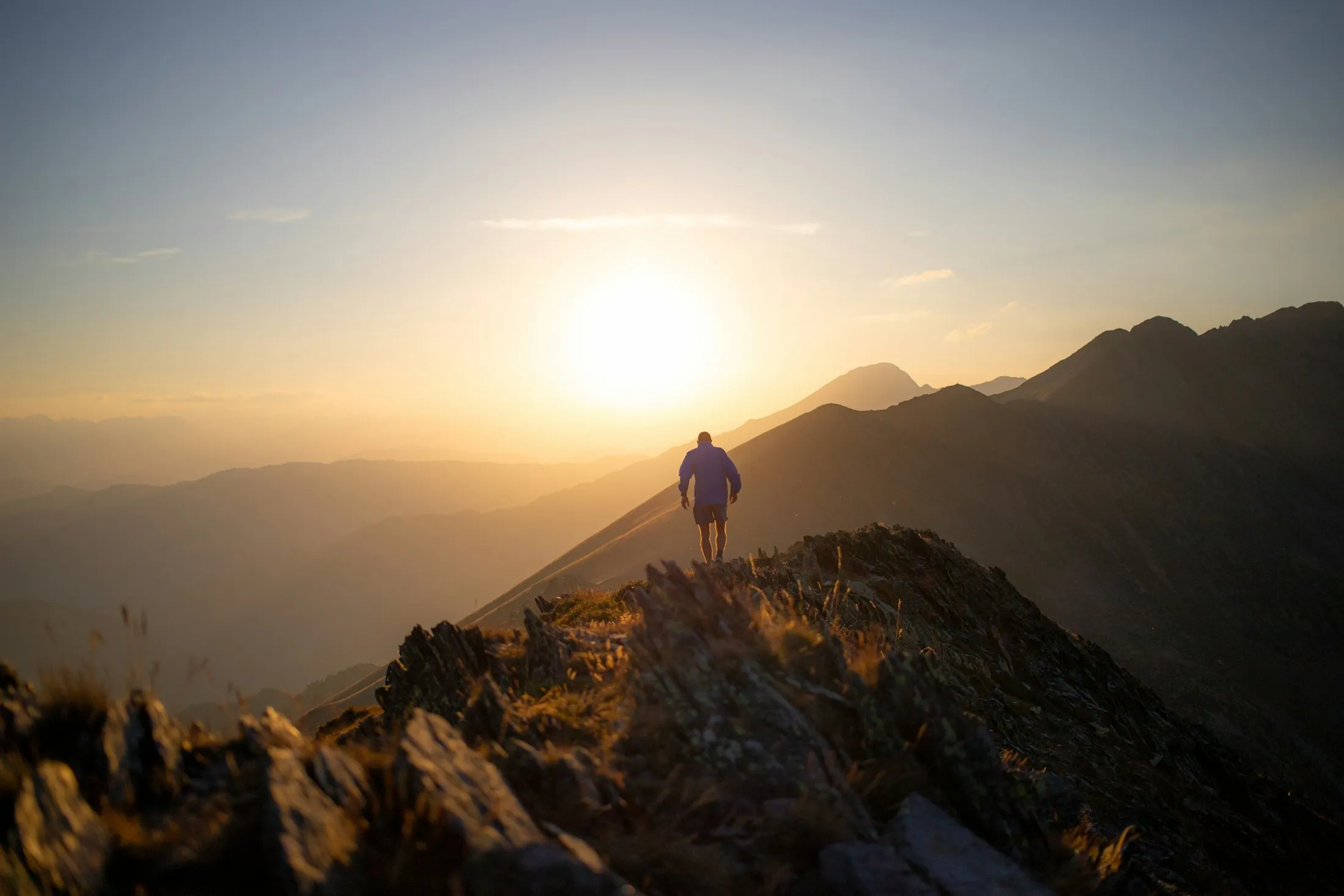 A tiny figure on a golden ridgeline at sunset